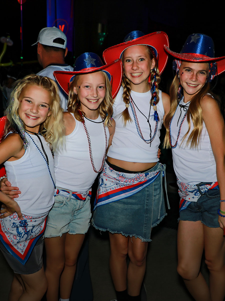 Four dancers in red, white, and blue Wrap Party costumes smiling together